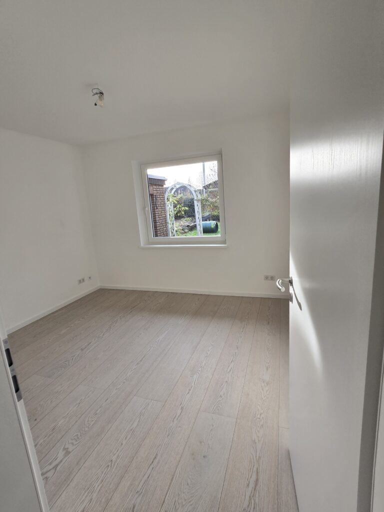 Geöffnete weiße Innentür mit Blick auf ein Fenster im hellen Raum
