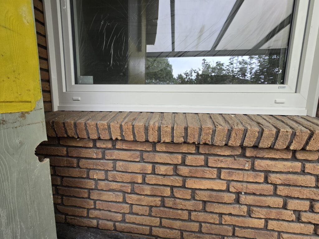 Fenster mit weißem Rahmen über einer Ziegelwand