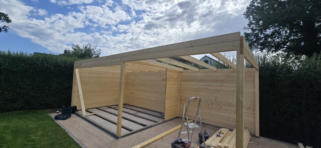 Holzwände und Dachbalken während des Gartenhaus-Aufbaus