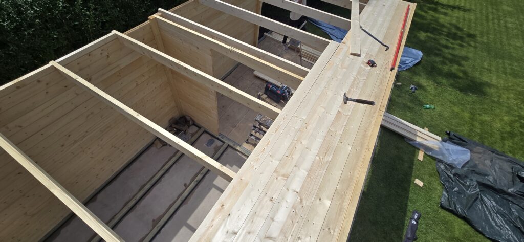 Holzwände und Dachbalken während des Gartenhaus-Aufbaus