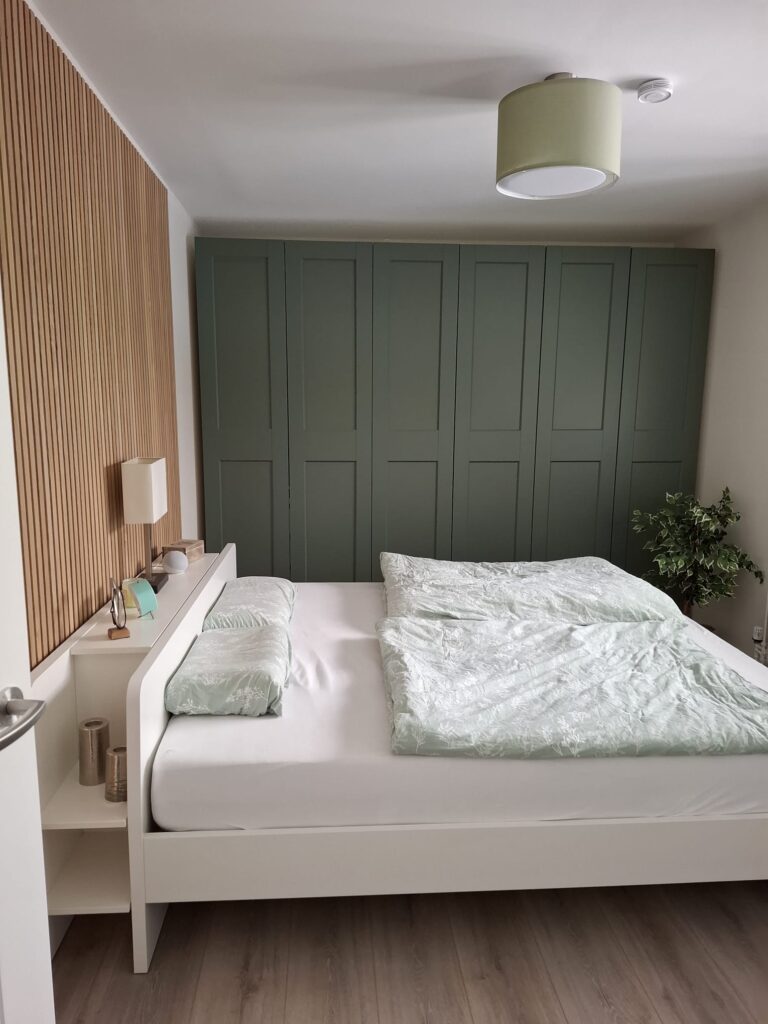 Holzlamellenwand neben einer Schrankanlage im Schlafzimmer